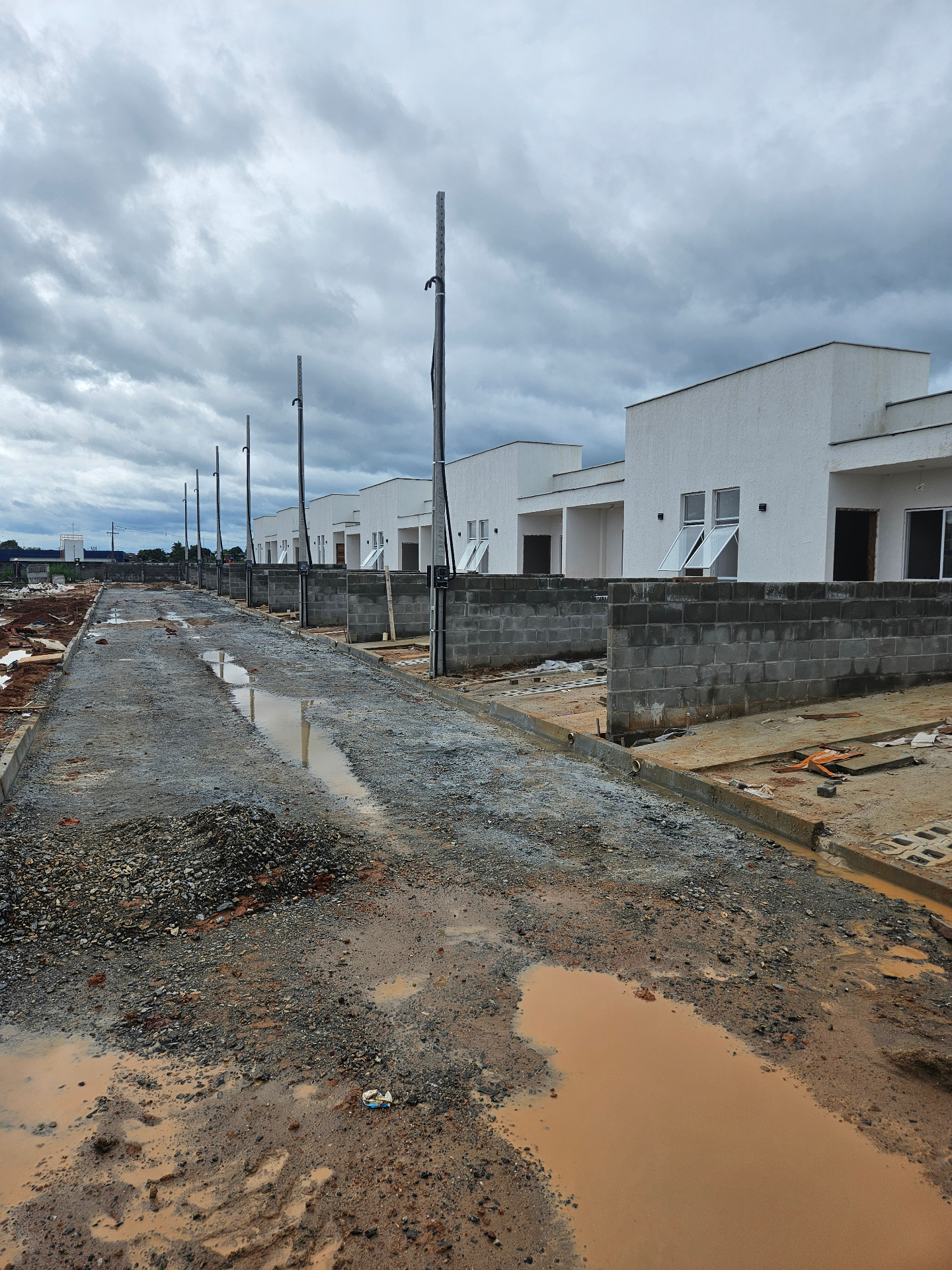 Implantação residencial em execução com unidades térreas alinhadas e infraestrutura externa em obra
